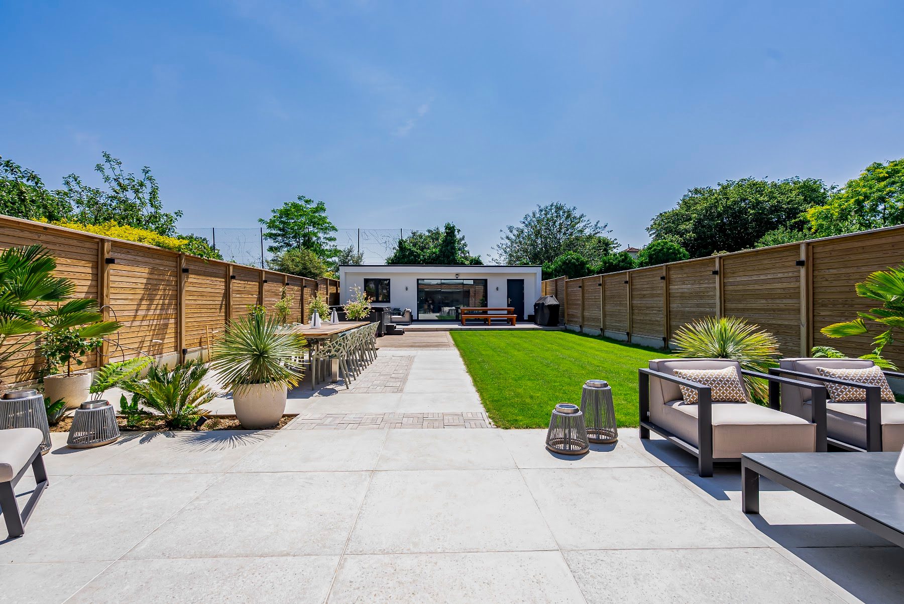 Landscaped rear garden with a generous lawn, structured planting beds and a paved terrace