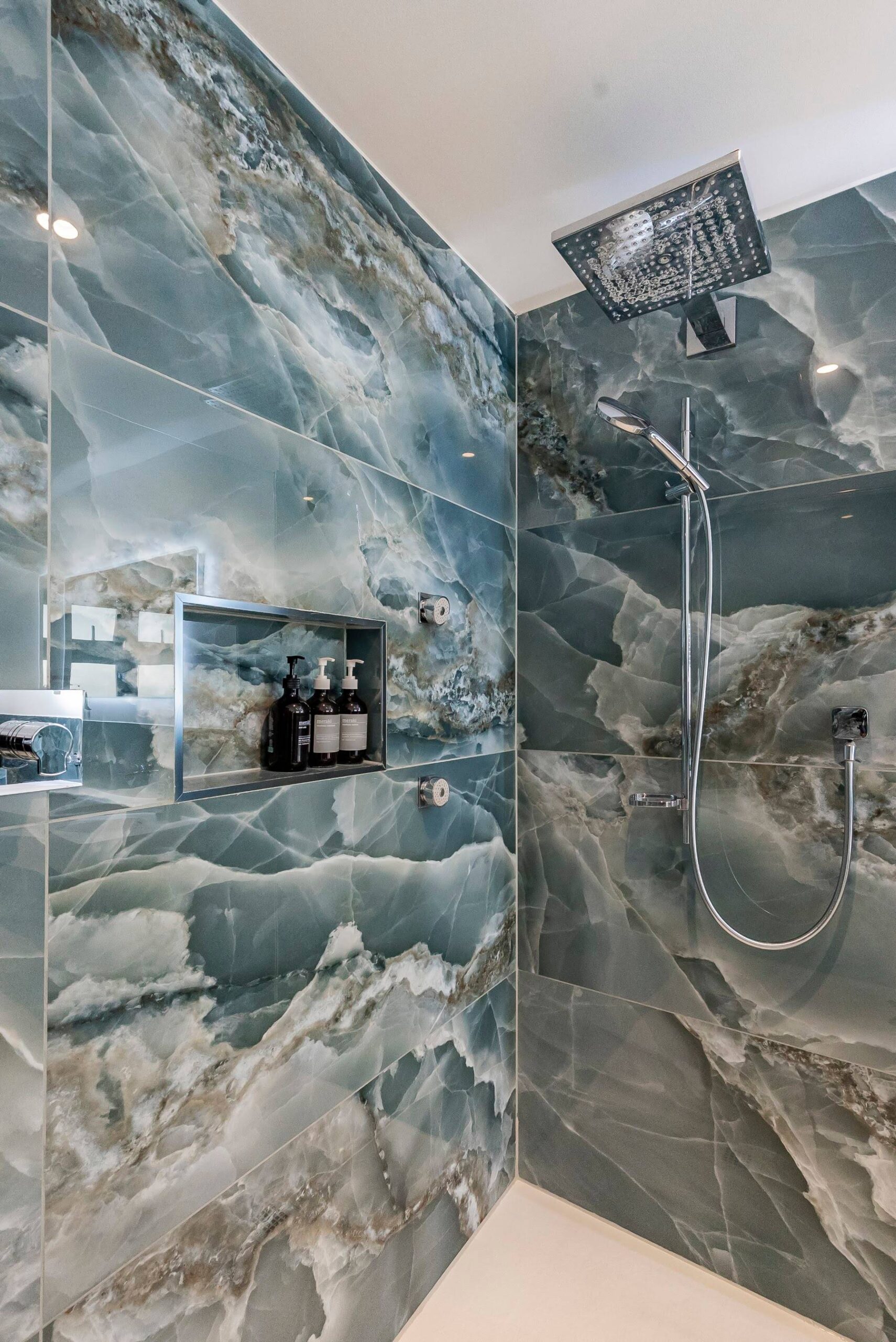 Walk-in shower finished in dramatic green marble-effect surfaces